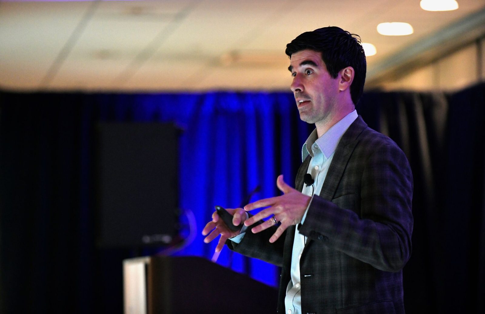 Armando J. Perez-Carreno speaking on stage with a slide clicker in his hand