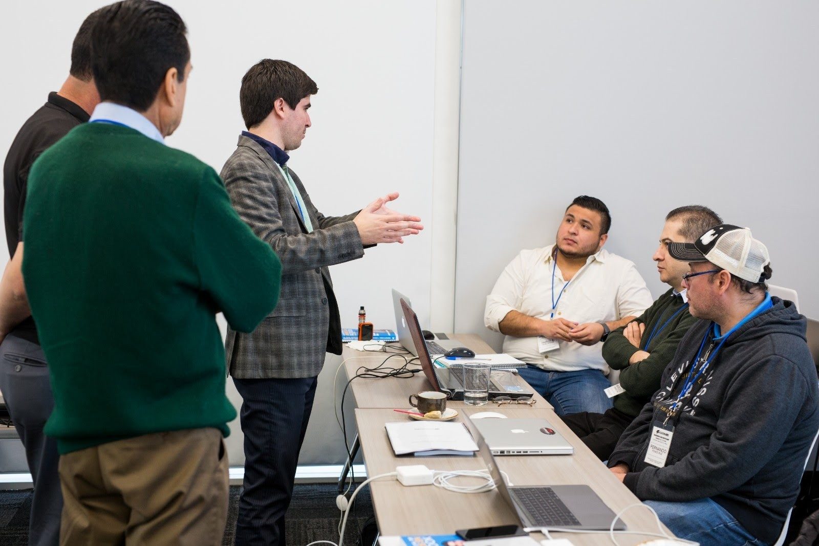 Armando J. Perez-Carreno in a plaid blazer talking with attendees seated at laptops during a workshop